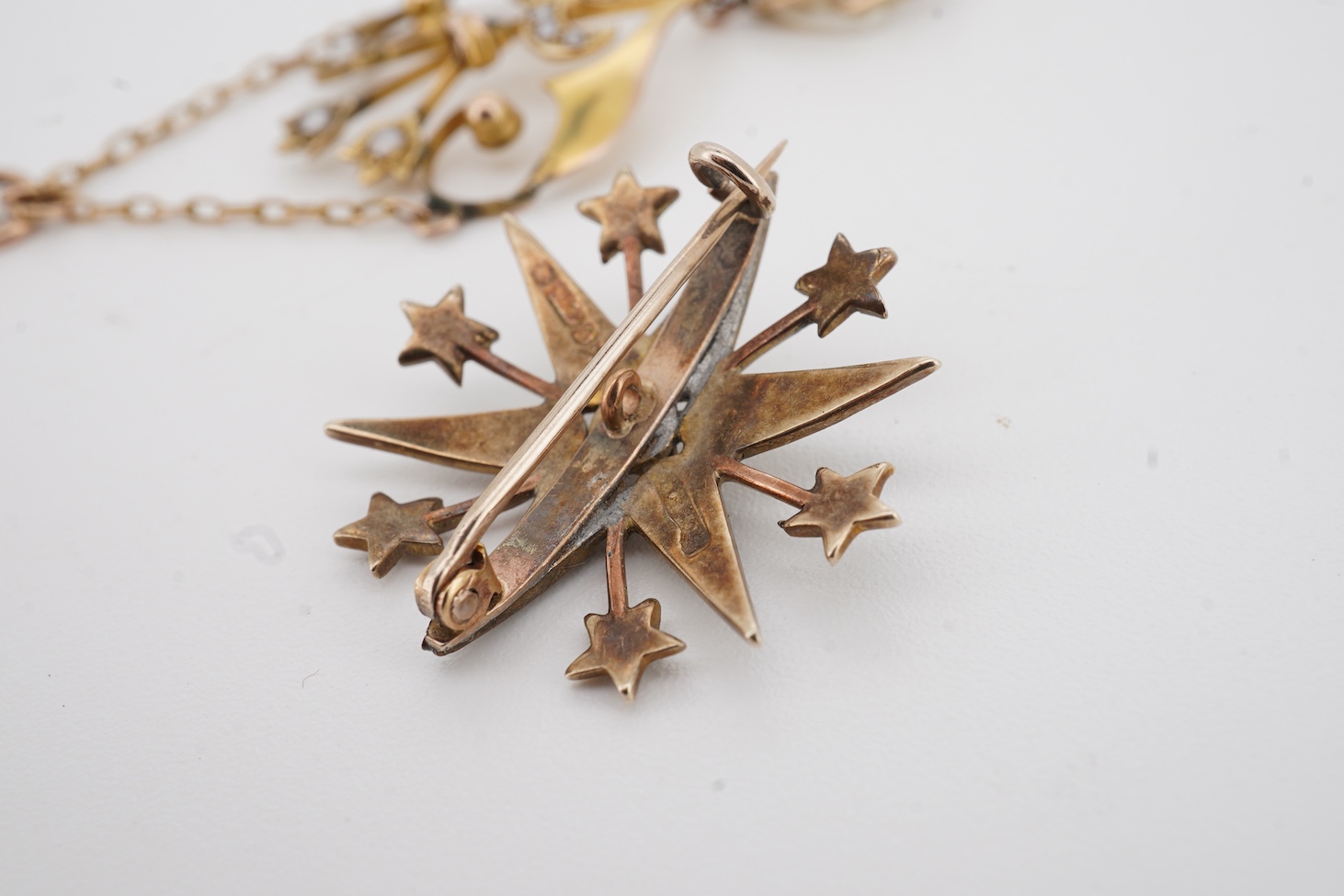 An Edwardian Art Nouveau 9ct, seed and baroque pearl set drop pendant, overall 55mm, together with an Edwardian style 9ct gold and seed pearl set starburst brooch.